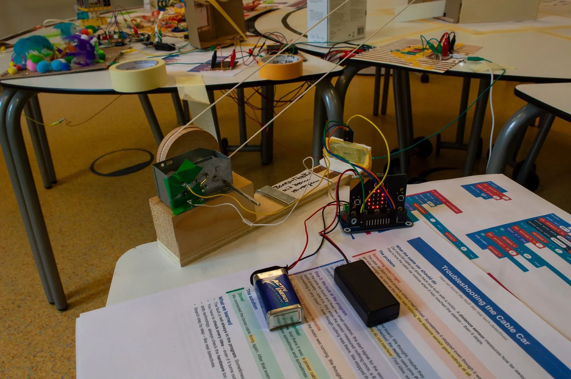 Seilbahnwinde mit micro:bit, daneben das Blatt: Troubleshooting the Cable Car